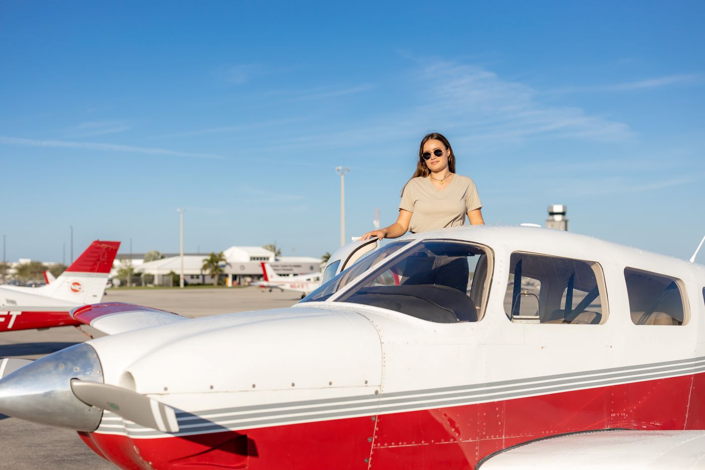 A student with sunglasses standing at the door of an airplane